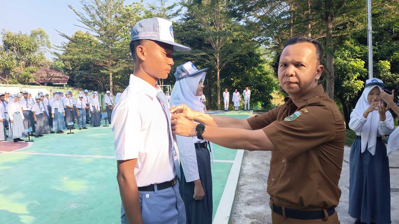 Kepala SMAN 8 Kota Lubuk Linggau, Himawan Sutanto, MPd menyematkan tanda peserta MPLS -foto muhammad yasin/koranlinggaupos.id-
