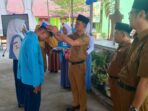 Kepala SMAN Purwodadi, Agus Salim memasang perlengkapan MPLS kepada perwakilan siswa baru, didampingi Ketua Pelaksana MPLS, Indramaya pada acara pembukaan MPLS, Senin 13 Juli 2026. Foto : SMAN Purwodadi