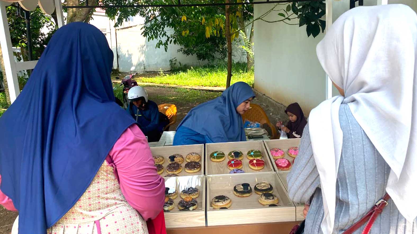 Seorang pembeli memilih donat kentang dengan aneka topping warna-warni di sebuah booth sederhana di Kelurahan Taba Jemekeh, donat seharga Rp4.000 per buah. FOTO: DOK. PUTRI ANANDA